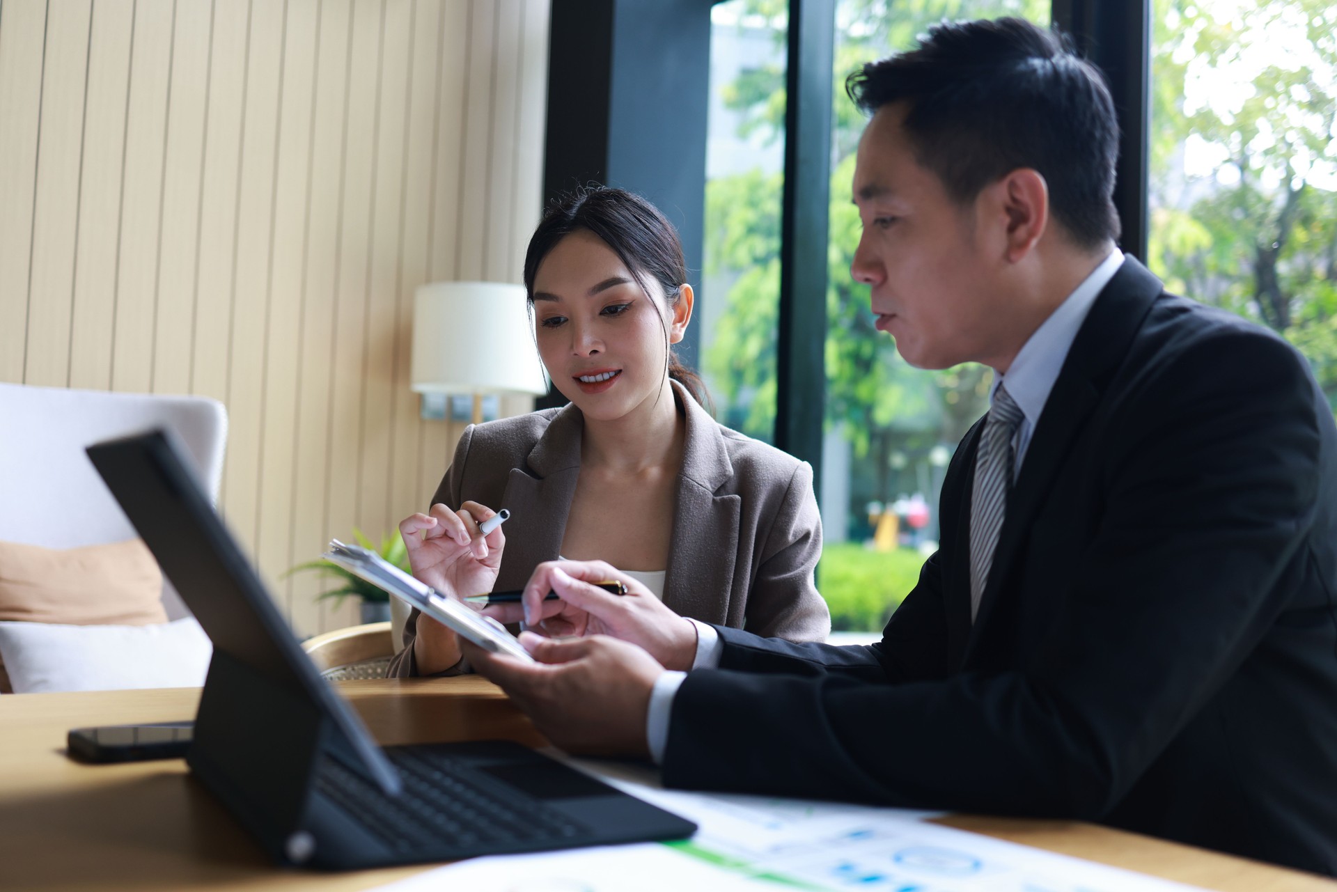 Businesswoman and businessman manager boss executive company office at co-working space talk discussion financial report and  partnership together look at computer notebook tablet investment customer job online