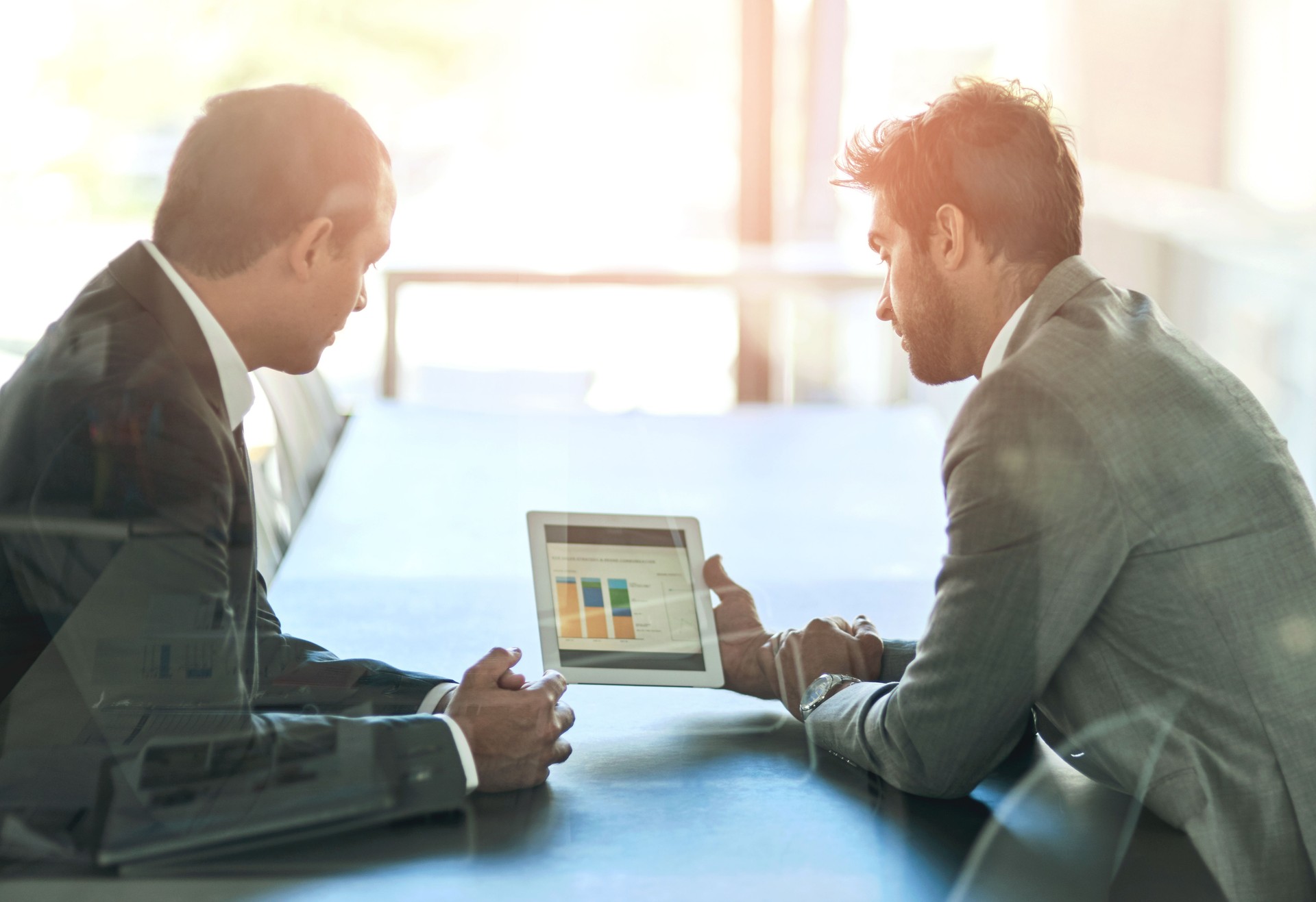 Business, men and discussion with graphs on tablet for trading, performance and financial charts for growth. Partnership, communication and technology with statistics for investment trends and review